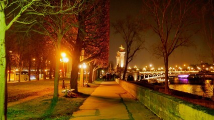 Promenade au bord de la Seine, sur les quais, dans un Paris fortement éclairé par des lampadaires...