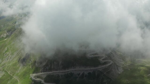 Beautiful roads of Romania. 4K aerial video with Transalpina road on top of the mountains with big clouds above. Curved waving road.