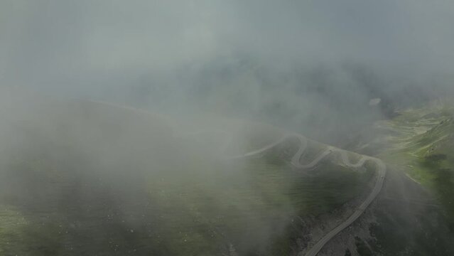Beautiful roads of Romania. 4K aerial video with Transalpina road on top of the mountains with big clouds above. Curved waving road.