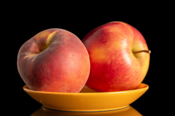 One red organic apple and peach on yellow ceramic saucer, macro, isolated on white background.
