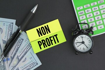 calculator, pen, paper money and colored paper with the word non-profit