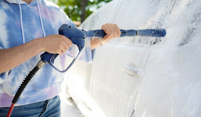 Girl washing a white car in a self-service car wash station. Wash car self-service station.