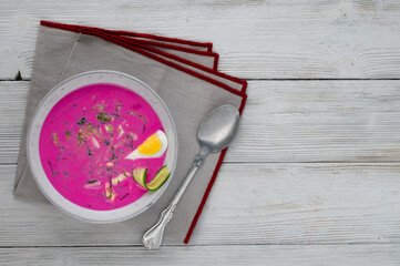 Chłodnik or Šaltibarščiai is traditional lithuanian and polish soup. Cold summer soup of beetroot, kefir, cucumbers, eggs, dill and potatoes in a grey bowl on a grey table. Summer Healthy food.