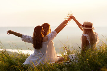 Lovely ladies drinking wine at sunset. Summer happy mood. Girlfriends relaxing on summer sunset...