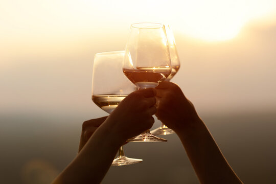 Friends holding glasses of wine at sunset. Chin-chin. Copy space.	
