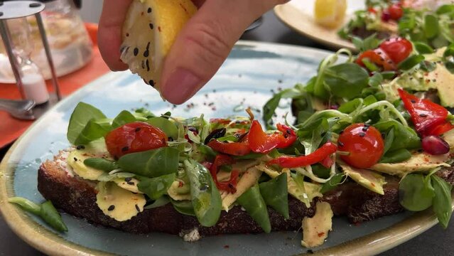 Avocado toast being sprinkled with lemon juice