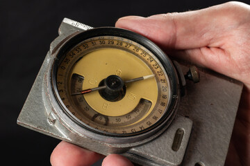 Old mining compass in hand on dark background close up