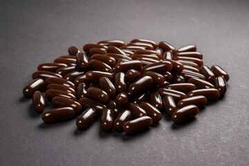 Lecithin gel pills capsule on dark background. Soy lecithin benefits for skin, digestion, lower cholesterol.