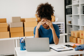 Calm curly brunette dark skinned woman on desk in modern office of fashion designer and holds tablet and smartphone.