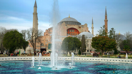 Naklejka premium Istanbul, Turkey - February 2023: Ayasofya Mosque. Beautiful square with growing trees and fountains in front of Hagia Sophia Cami