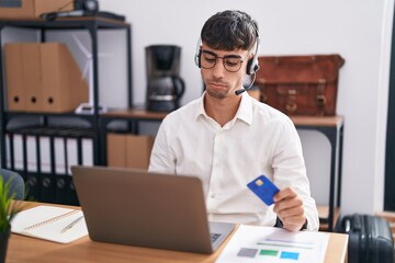 Young hispanic man working using computer laptop holding credit card depressed and worry for distress, crying angry and afraid. sad expression.