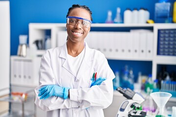 Fototapeta premium African american woman scientist smiling confident standing with arms crossed gesture at laboratory