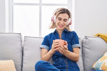 Young woman listening to music drinking coffee at home