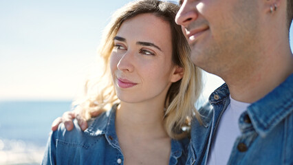 Man and woman couple smiling confident hugging each other at seaside