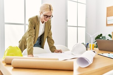 Young blonde woman architect looking house plans smiling at office