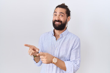 Hispanic man with beard wearing casual shirt pointing aside worried and nervous with both hands,...