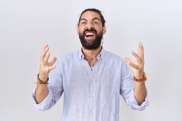 Fototapeta premium Hispanic man with beard wearing casual shirt crazy and mad shouting and yelling with aggressive expression and arms raised. frustration concept.