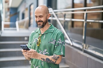Young bald man smiling confident using smartphone at street