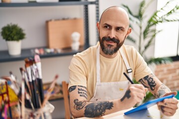 Young bald man artist smiling confident drawing on touchpad at art studio