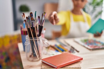 African american woman artist reading book holdng paintbrush at art studio