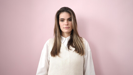Fototapeta premium Young beautiful hispanic woman standing with serious expression over isolated pink background