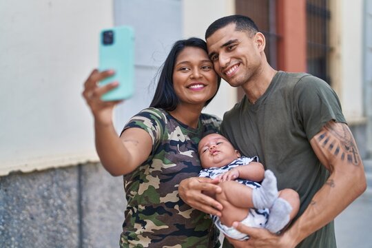 Hispanic family hugging each other making selfie by smartphone at street