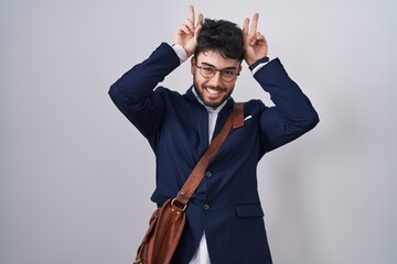 Hispanic man with beard wearing business clothes posing funny and crazy with fingers on head as bunny ears, smiling cheerful