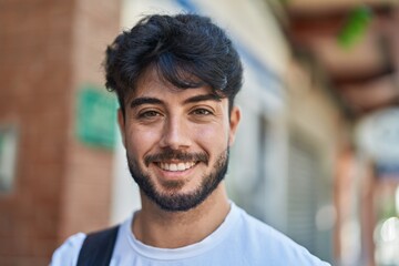 Obraz premium Young hispanic man smiling confident wearing backpack at street