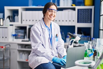 Young woman scientist using laptop at laboratory
