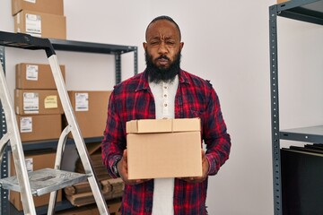 African american man working at small business ecommerce puffing cheeks with funny face. mouth inflated with air, catching air. - obrazy, fototapety, plakaty