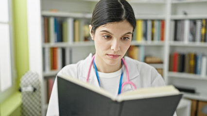 Young beautiful hispanic woman doctor reading book at library university