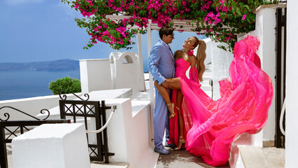 Summer love. Beautiful happy young couple in elegant wedding clothes is posing in Fira in...