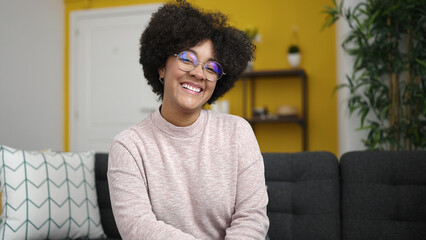 Young african american woman smiling sitting on sofa at home