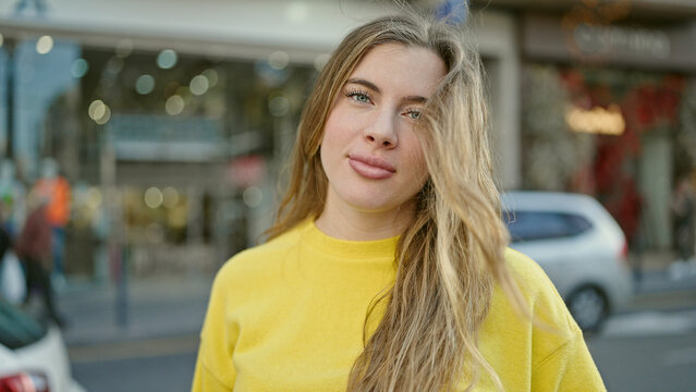Young blonde woman standing with relaxed expression at street
