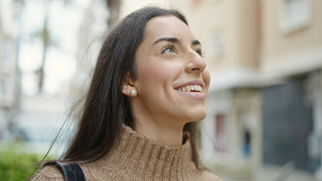 Young beautiful hispanic woman smiling confident looking to the sky at street