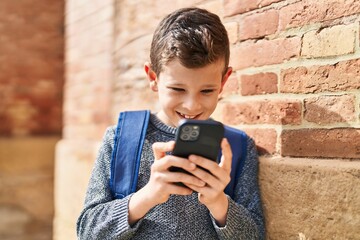 Fototapeta premium Blond child student using smartphone standing at street
