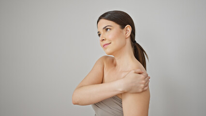 Young beautiful hispanic woman smiling confident applying lotion on shoulder over isolated white...