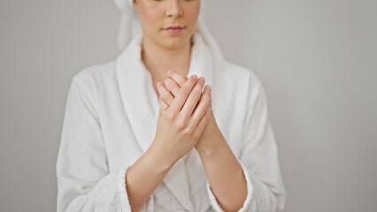 Young beautiful hispanic woman wearing bathrobe applying lotion on hands over isolated white background