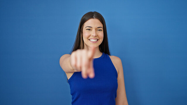 Young beautiful hispanic woman smiling confident pointing to camera over isolated blue background