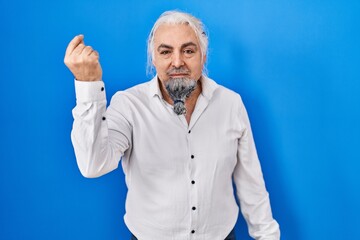 Middle age man with grey hair standing over blue background doing italian gesture with hand and fingers confident expression