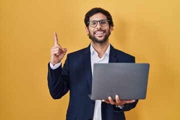 Handsome latin man working using computer laptop pointing finger up with successful idea. exited...