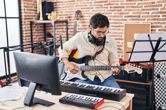 Young hispanic man musician playing electrical guitar at music studio