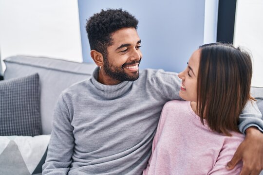 Man and woman couple hugging each other sitting on sofa at home