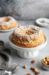 Round-shaped classic French dessert Paris Brest with almonds and hazelnuts on a white plate