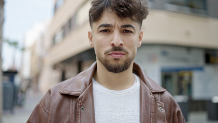Young arab man standing with serious expression at street