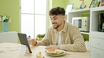 Fototapeta na wymiar Young arab man having video call eating at home