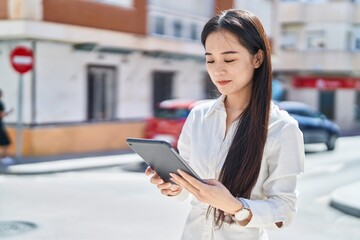 Young chinese woman smiling confident using touchpad at street