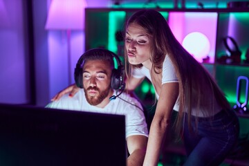 Young couple playing video games looking at the camera blowing a kiss being lovely and sexy. love expression.