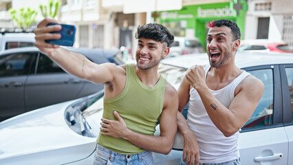 Two men couple having video call leaning on car at street