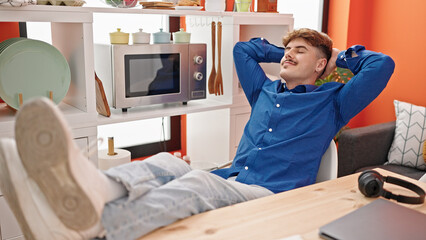 Young hispanic man relaxed with hands on head sitting on table at dinning room